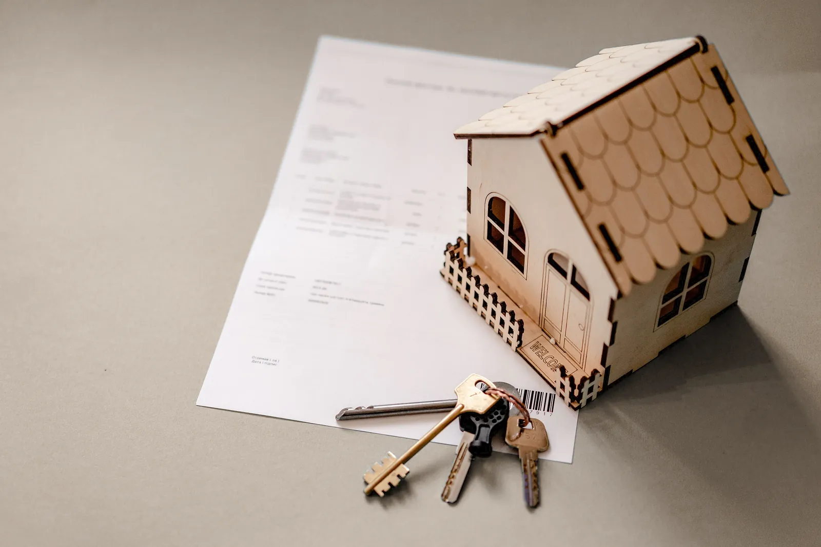 A model house and a set of keys resting on a closing document